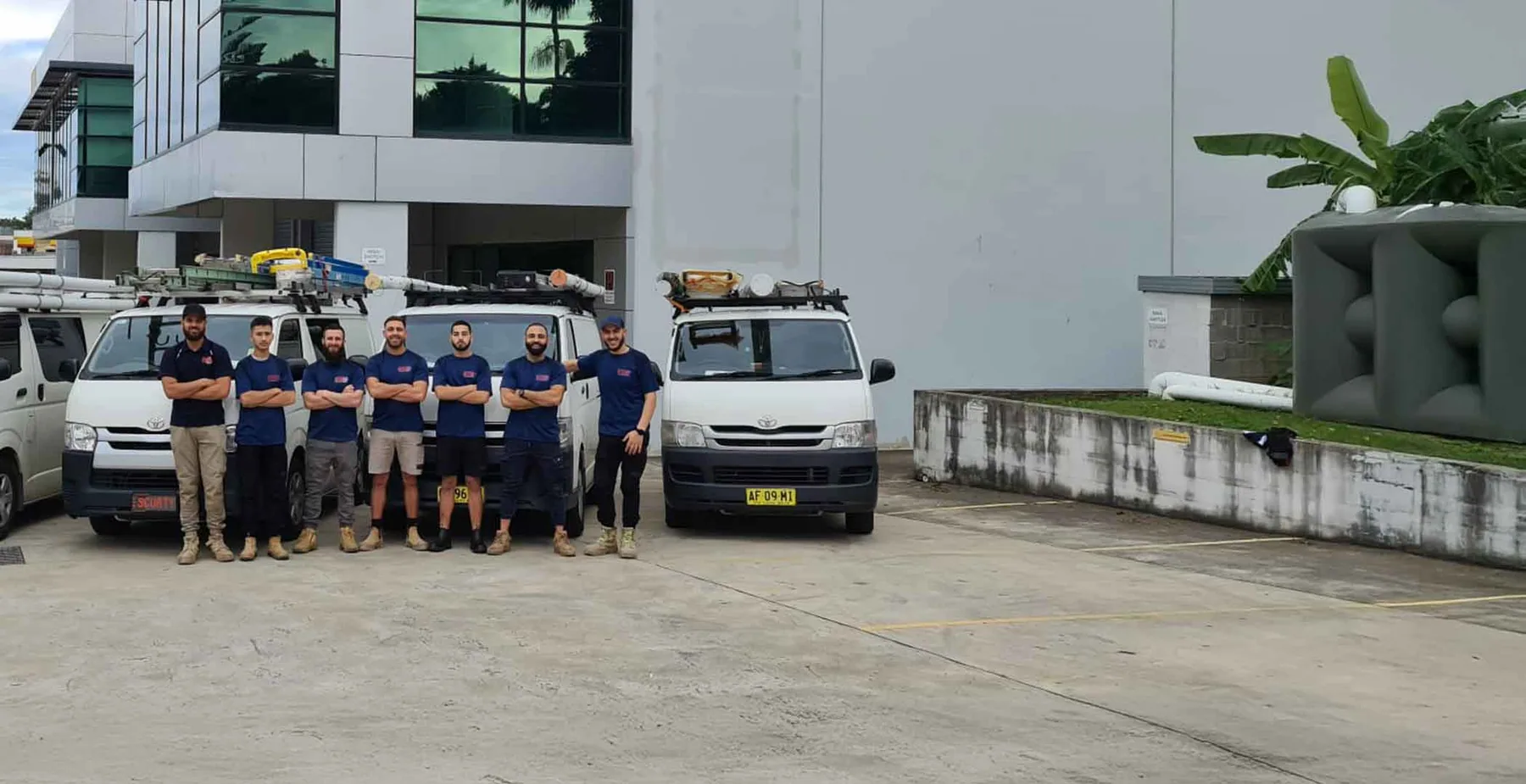 Meet the Ozy Wide Group team. Ozy Wide Group team standing with service vehicles in Sydney